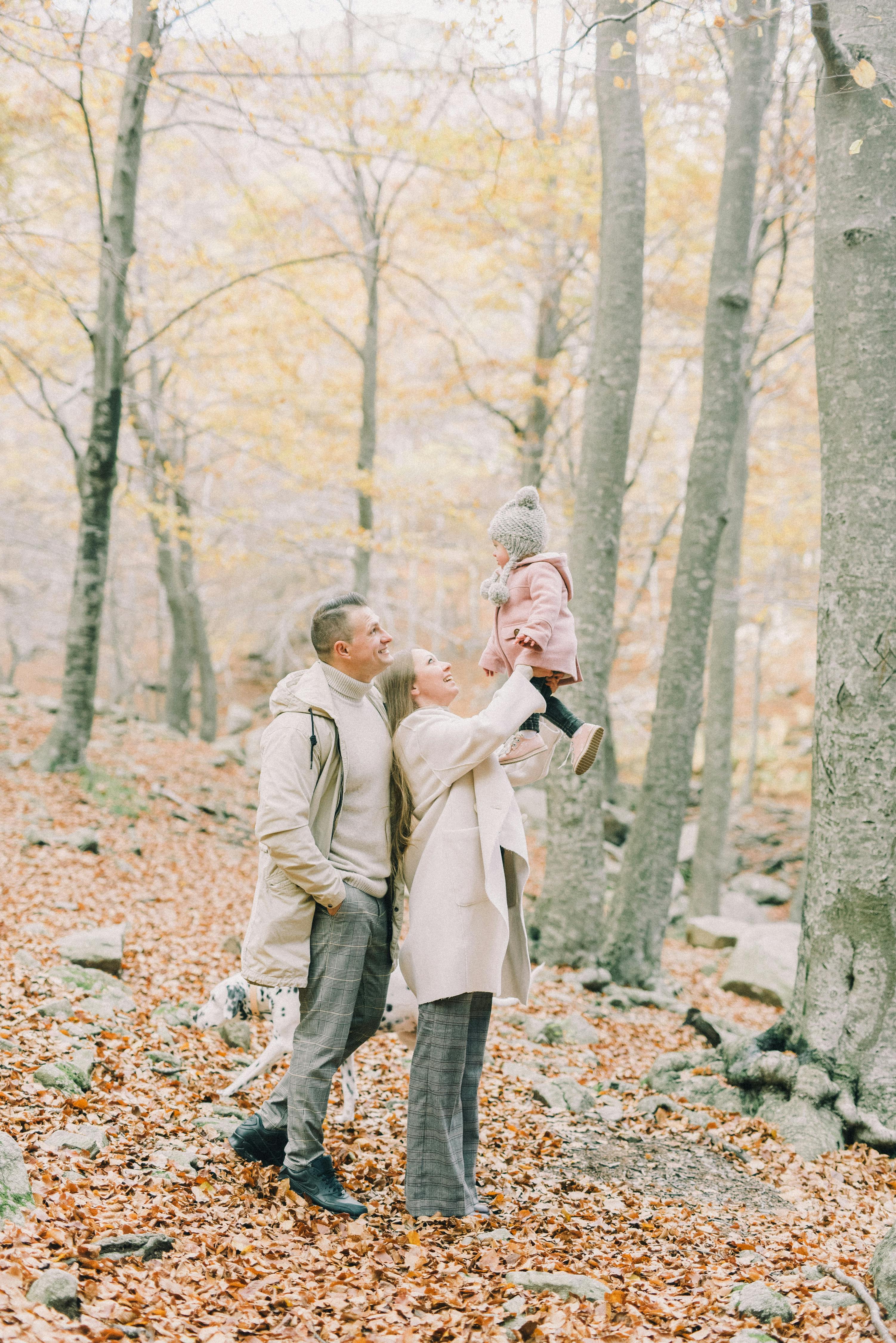 a happy couple with their child in the woods