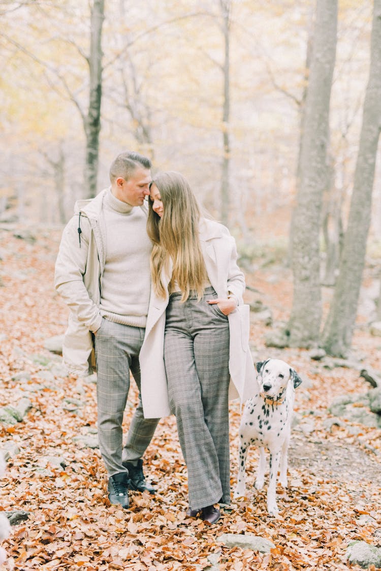 A Couple Walking In The Woods With Their Dog