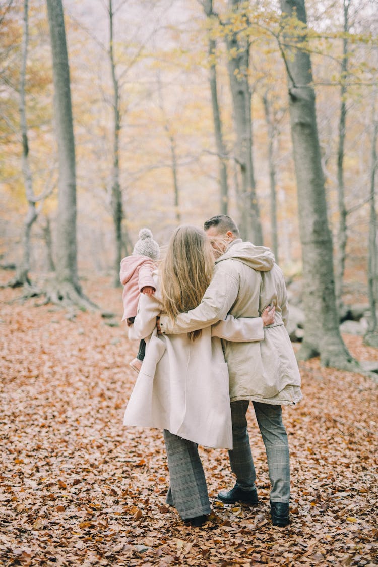 A Family Walking On Forest With Dry Leaves On Ground