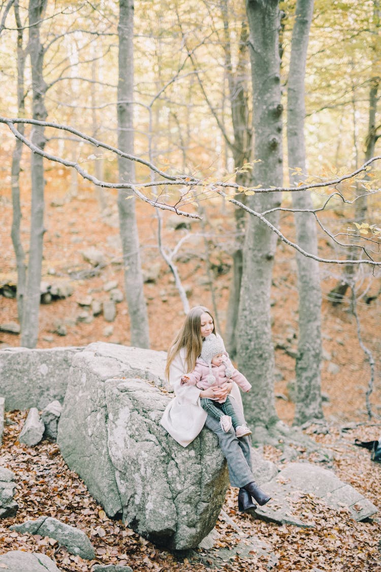 Woman Sitting On Gray Rock Carrying A Baby