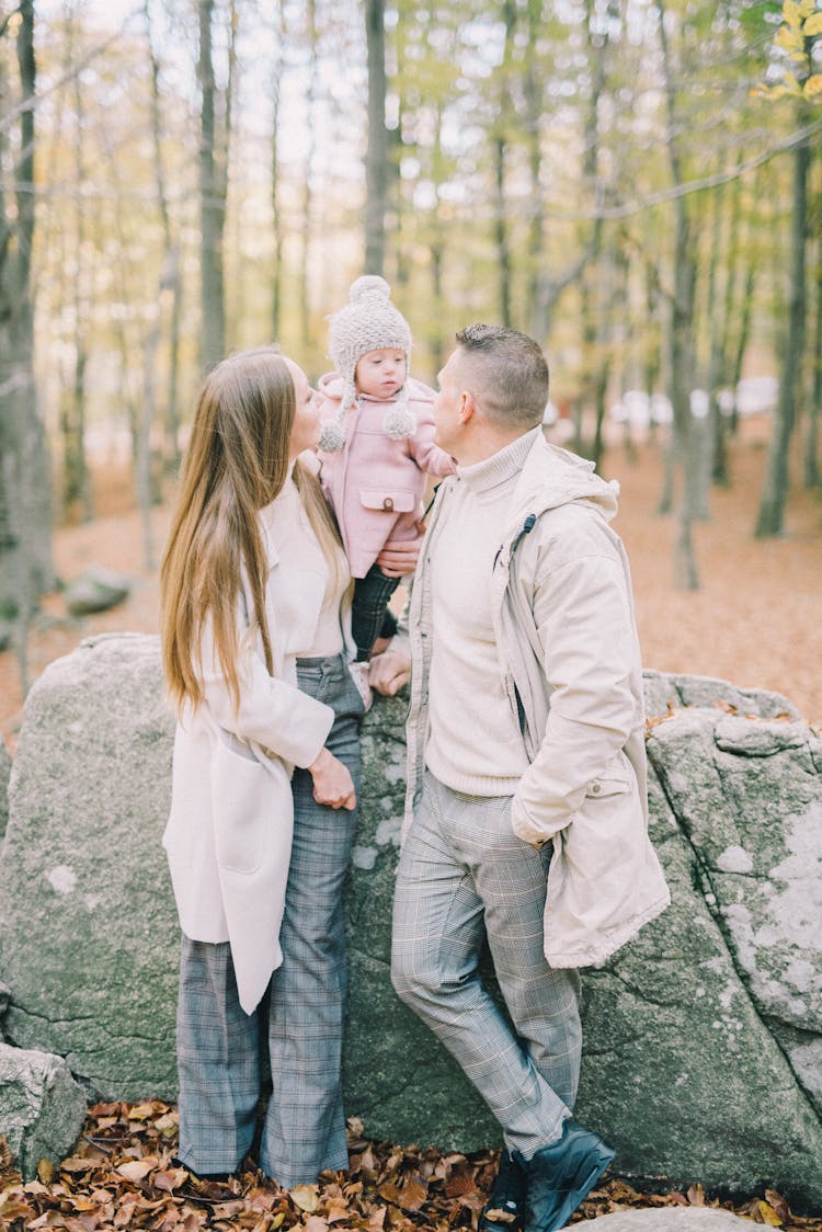 Couple With A Baby Standing Beside A Big Rock