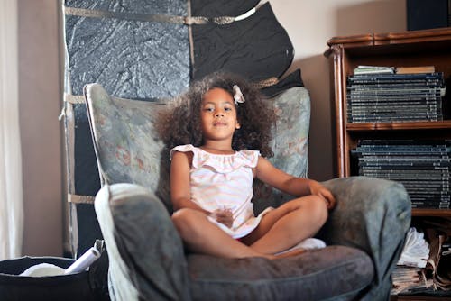 Portrait of a Girl with Curly Hair Sitting on an Armchair