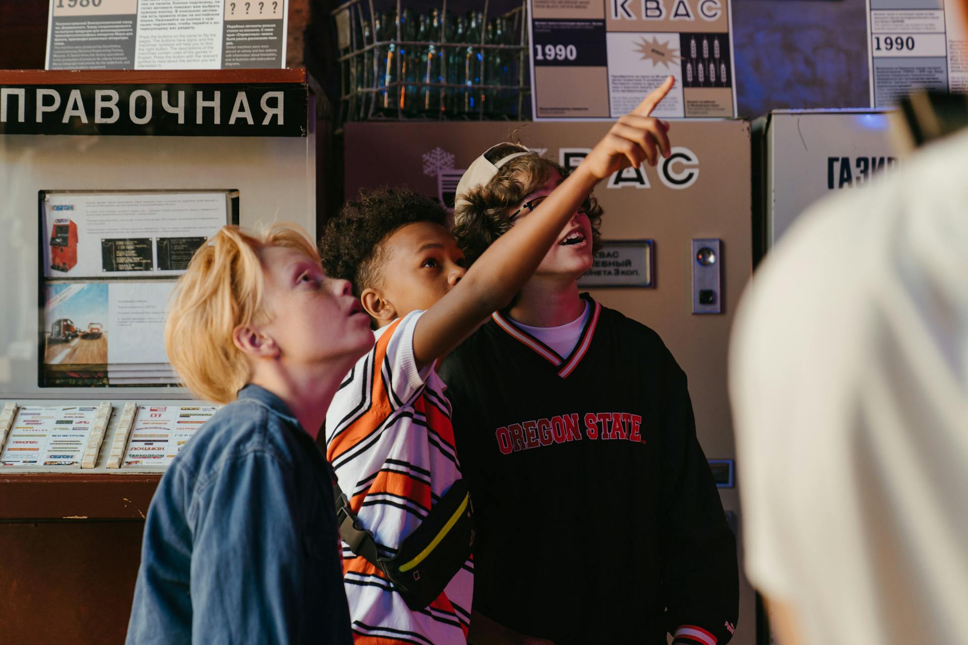 Three teenagers excitedly inspect a vintage vending machine in a retro setting, showcasing curiosity and fun.