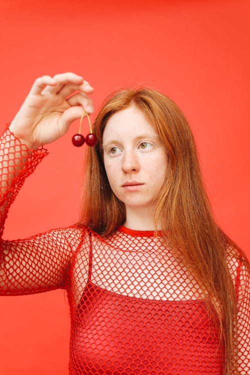 Woman in Red Fishnet Shirt Holding Cherries