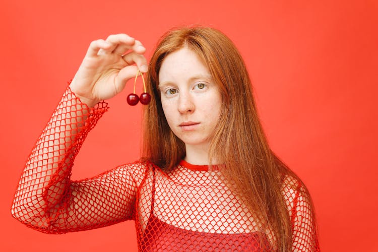 A Woman In A Red Outfit Holding Cherries