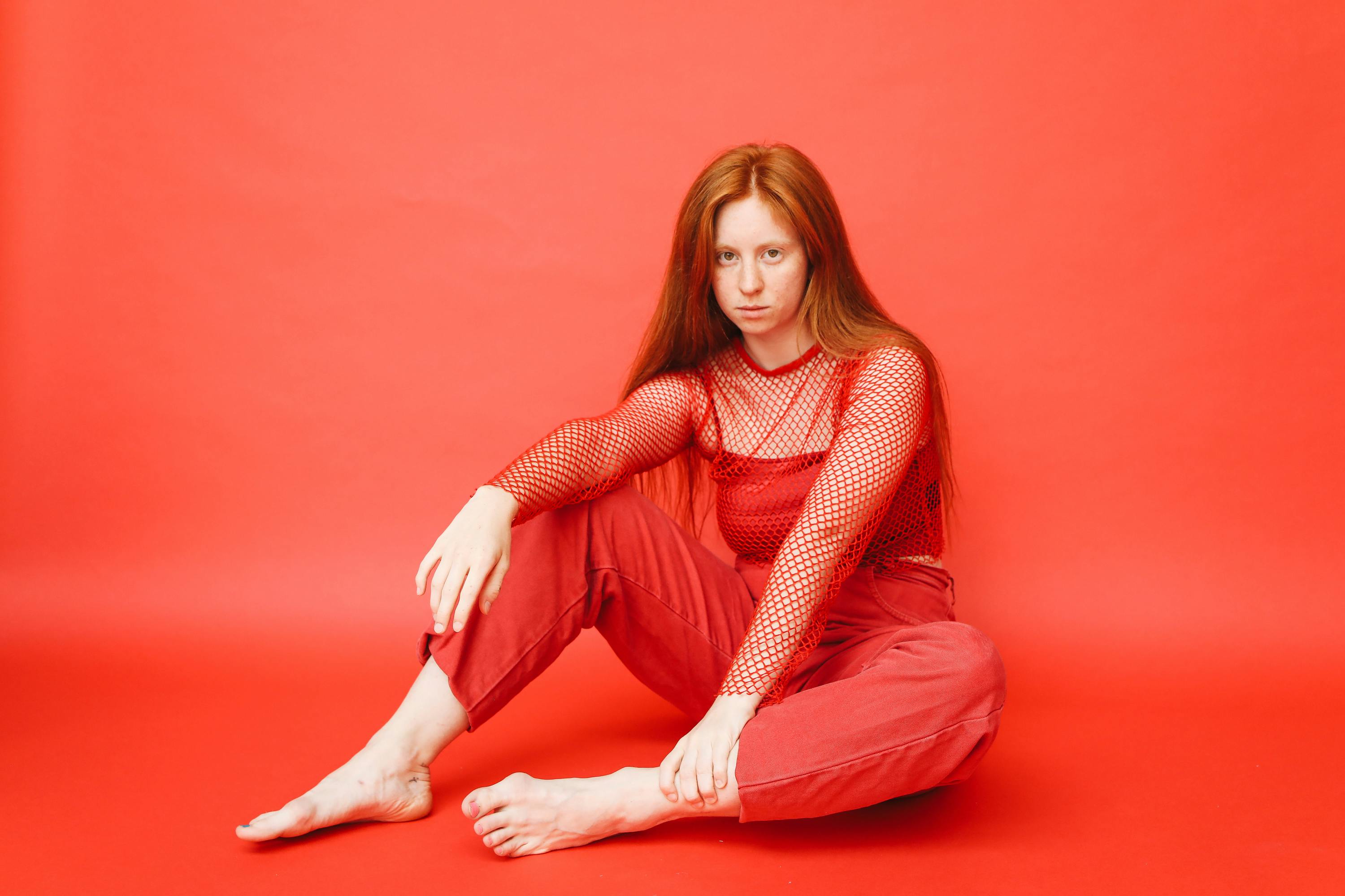 a woman in a red outfit posing while sitting on the floor