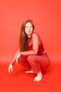 Woman in Red and White Checkered Long Sleeve Shirt and Red Pants Sitting on Red Floor