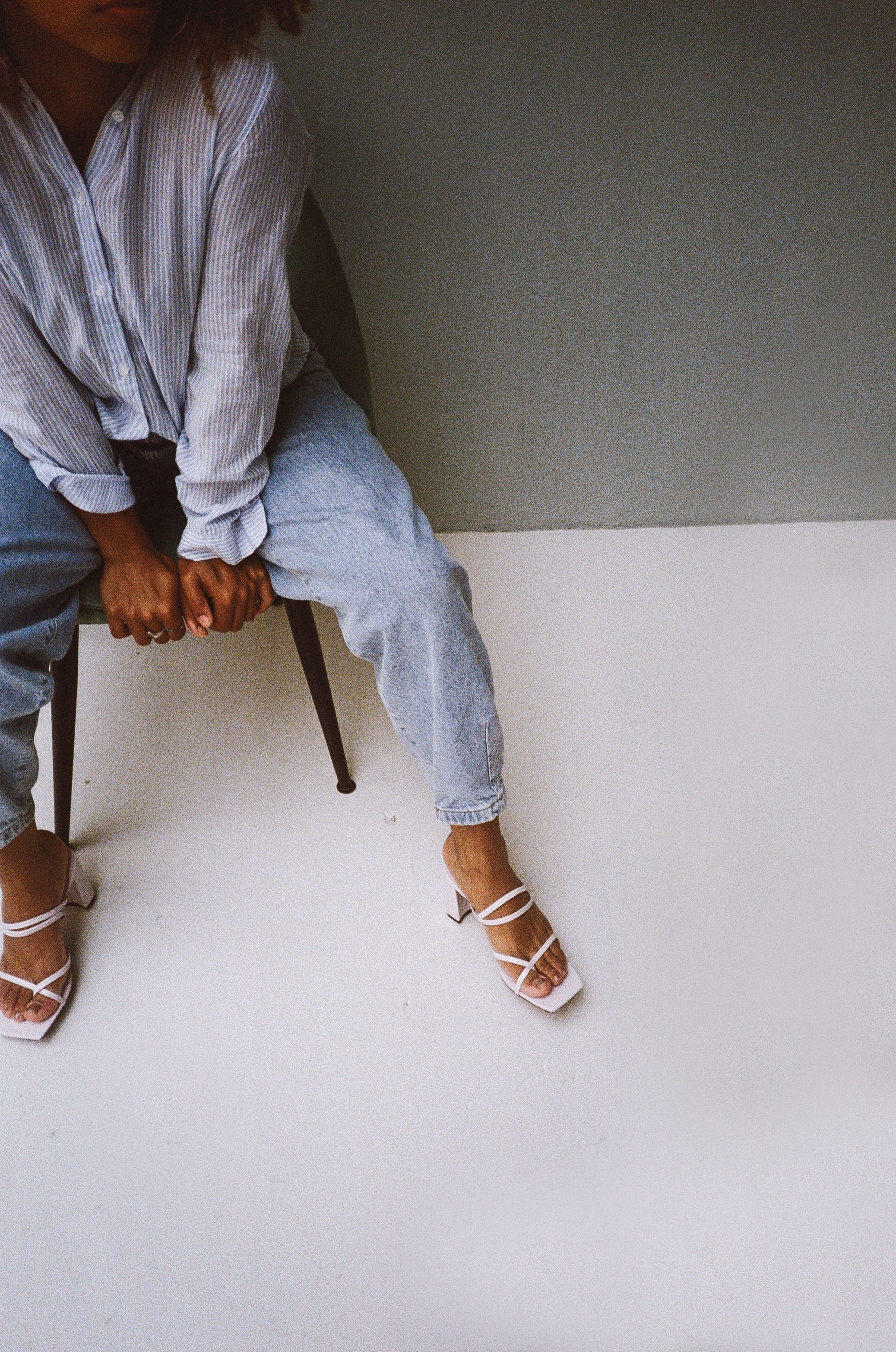 Pessoa estilosa sentada em ambientes internos com roupas casuais, mostrando um visual descontraído e moderno.
