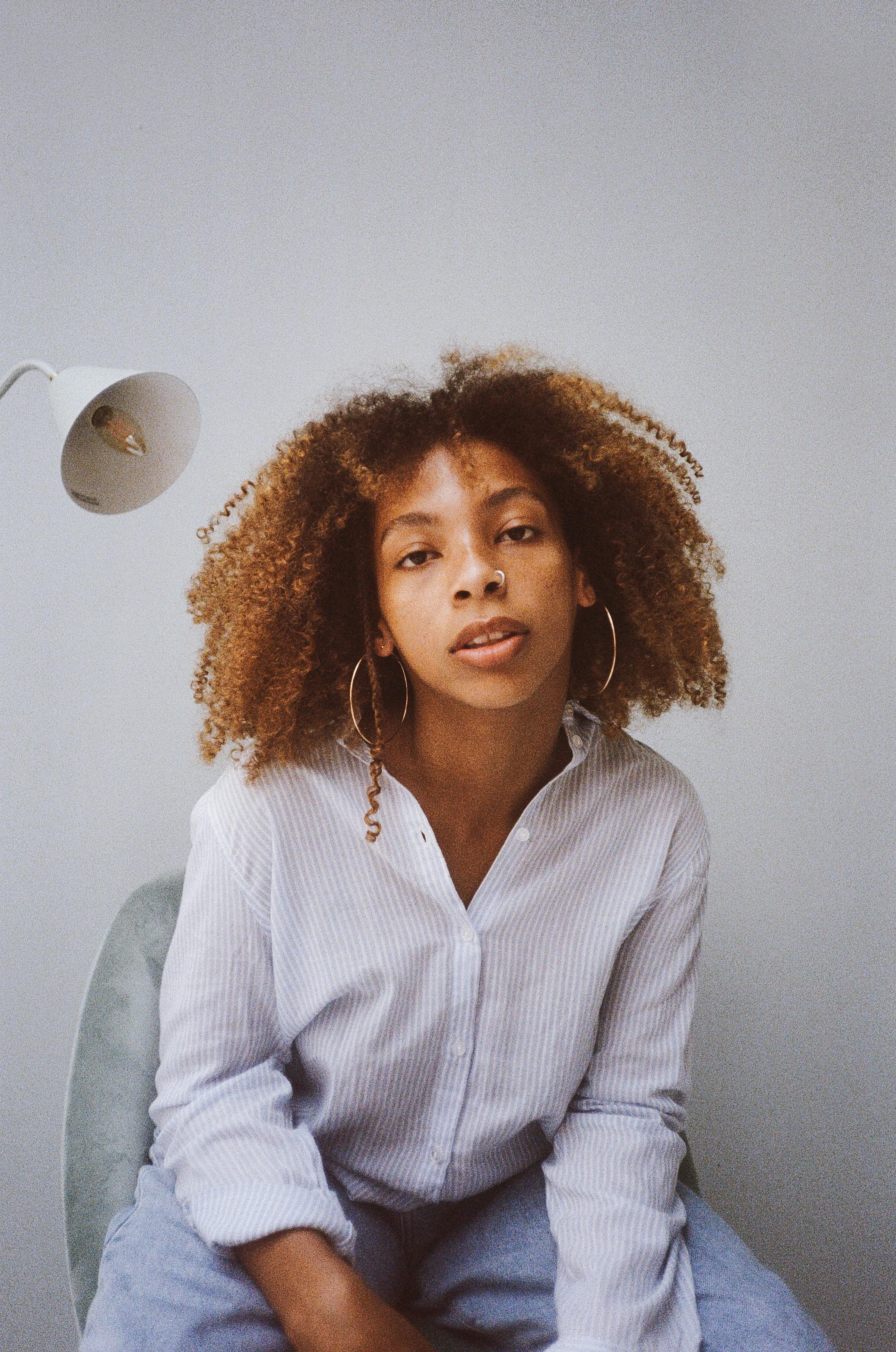 Elegant studio portrait of a woman with afro hair showcasing modern fashion and style.