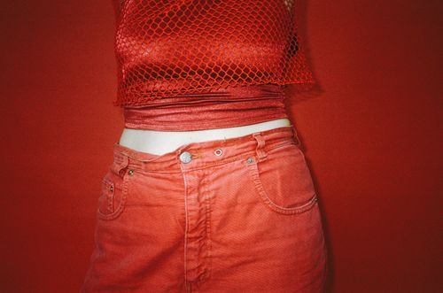 Free A close-up photo showcasing a stylish red fashion ensemble with a mesh top and pants against a red background. Stock Photo