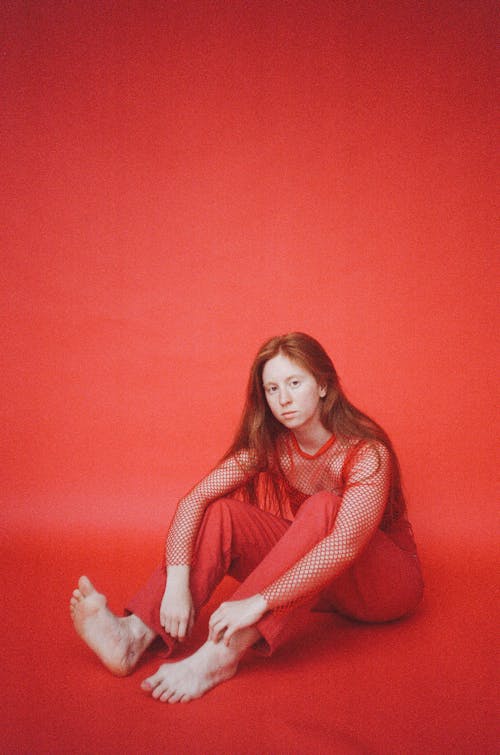 Barefooted Woman in Red Outfit Sitting on Red Floor