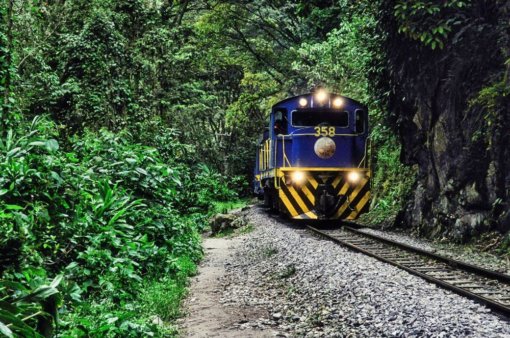 Locomotora azul del tren atravesando la selva andina hacia Aguas Calientes