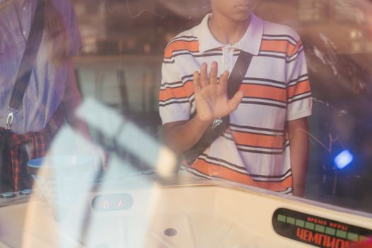 一名青少年透过反光窗好奇地看着街机