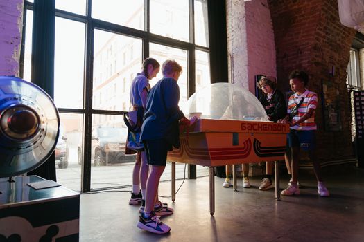 Group of teenagers playing an arcade game inside a nostalgic setting.