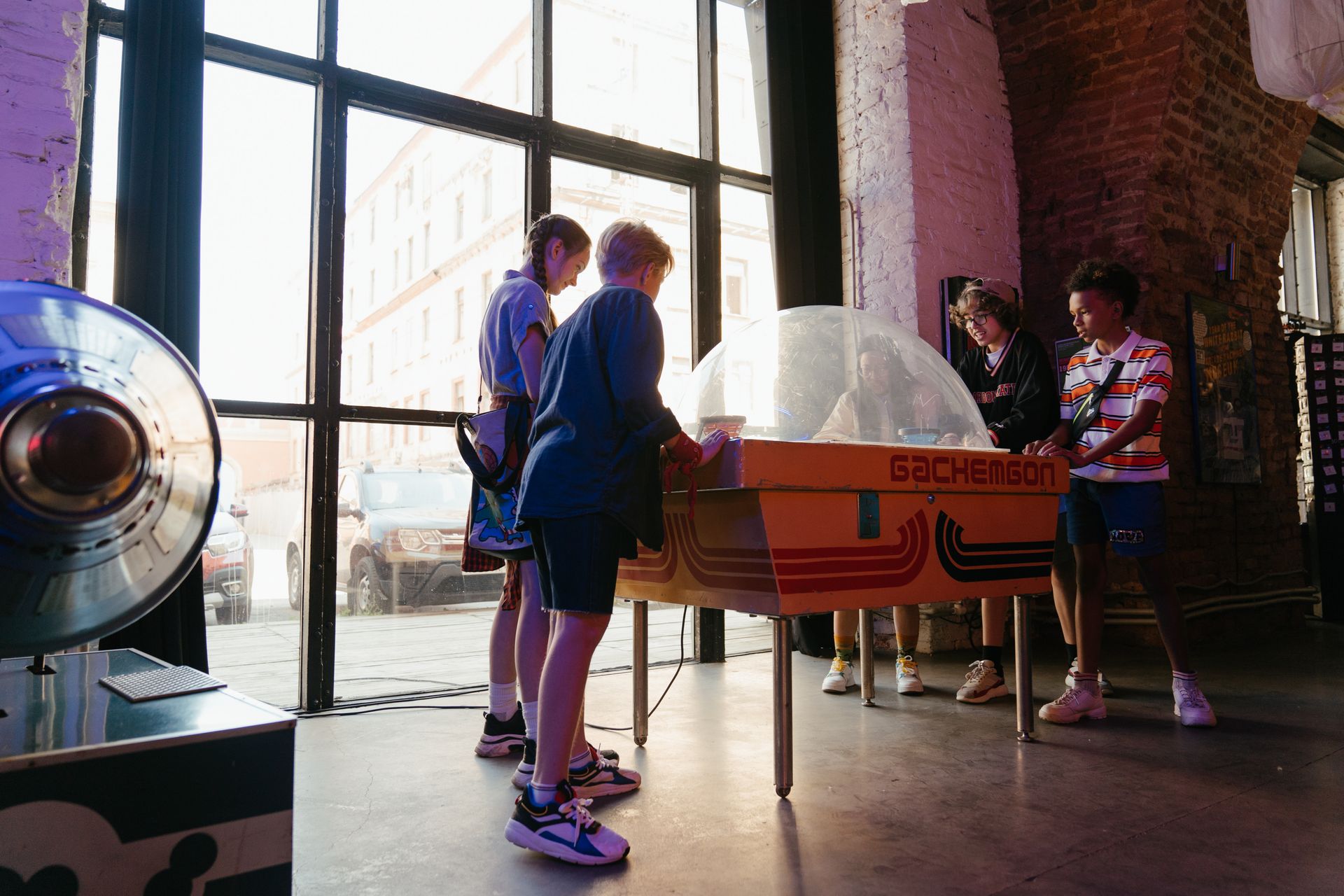 Group of teenagers playing an arcade game inside a nostalgic setting.
