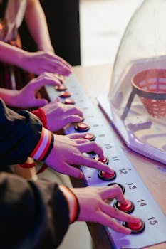 Close-up of hands engaging with a retro arcade button panel game indoors.