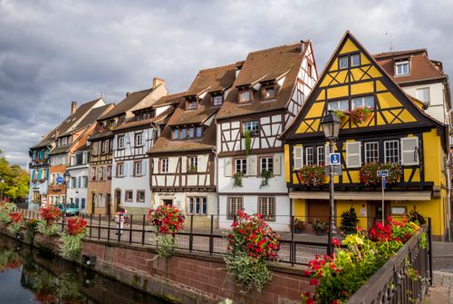 Free Picturesque view of traditional half-timbered houses in Colmar, France, with vibrant floral displays. Stock Photo