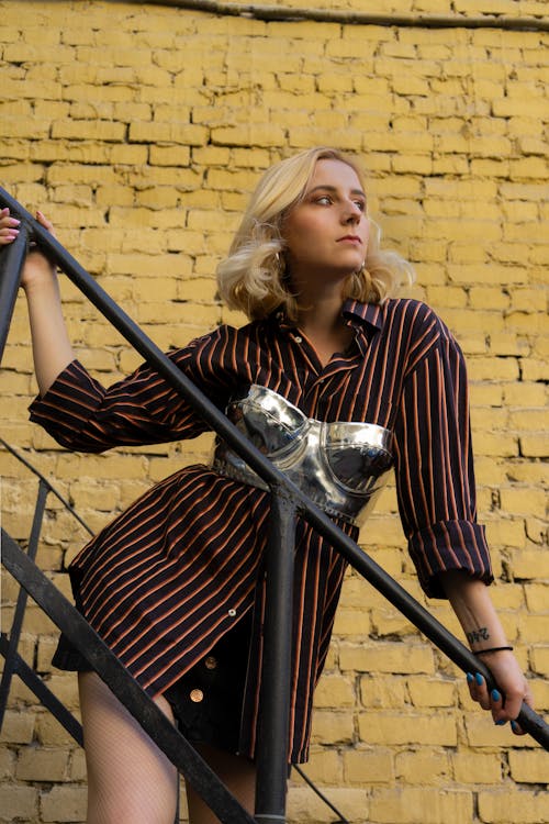 Young woman in trendy clothes standing on stairs