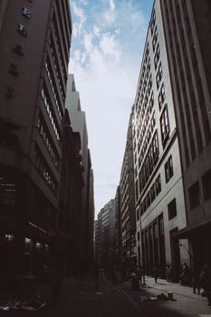 部分多云的天空下，城市摩天大楼形成了峡谷效应的戏剧性景象