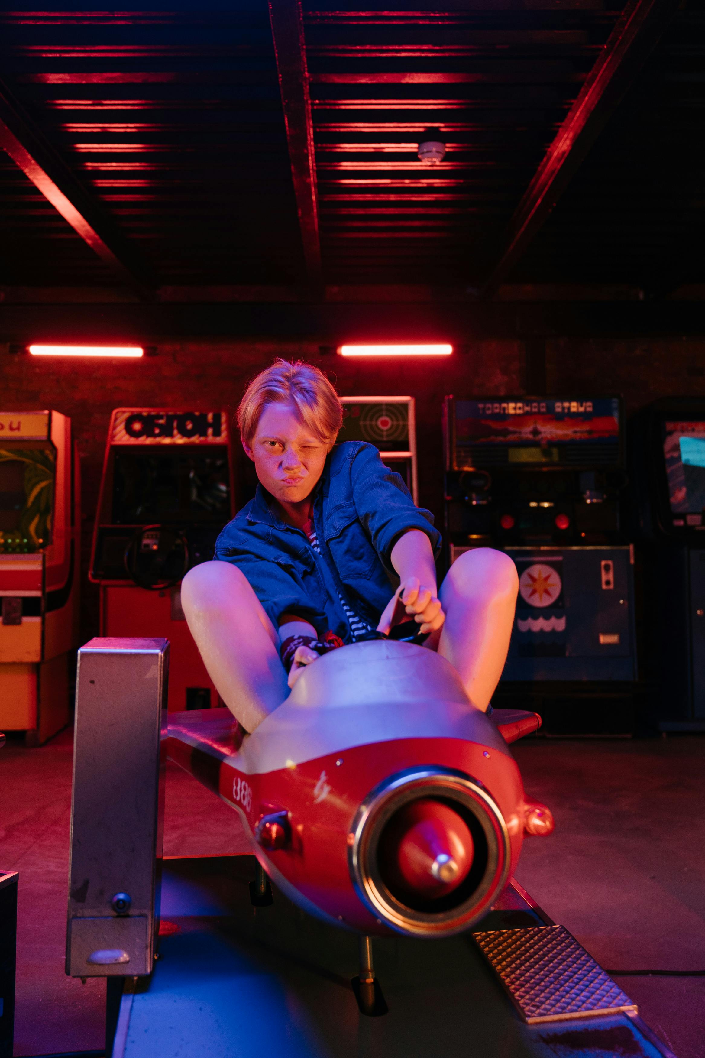 woman in blue denim jacket riding red ride on toy car