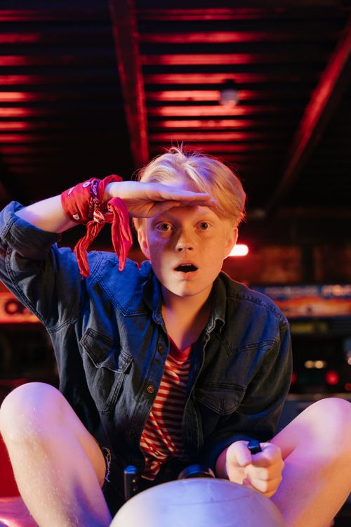 Free A happy teenage boy enjoys a fun ride in an amusement park with vibrant lights. Stock Photo