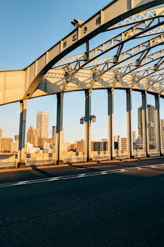 Urban scene of a steel bridge in Tokyo with skyscrapers at sunset.