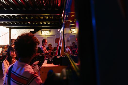 A group of teenagers playing games in a retro arcade setting, capturing the essence of 80s playtime.
