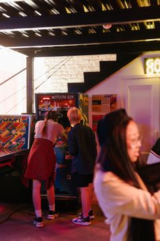 一群青少年在室内街机玩着复古游戏