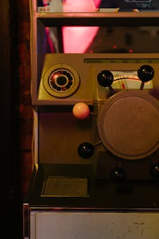 Close-up of a vintage gaming machine with a steering wheel in a dimly lit arcade.