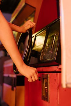 Close-up of hands engaged with a vintage arcade racing machine, evoking 80s nostalgia.