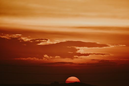 A breathtaking view of an orange sunset with silhouetted clouds in the horizon.