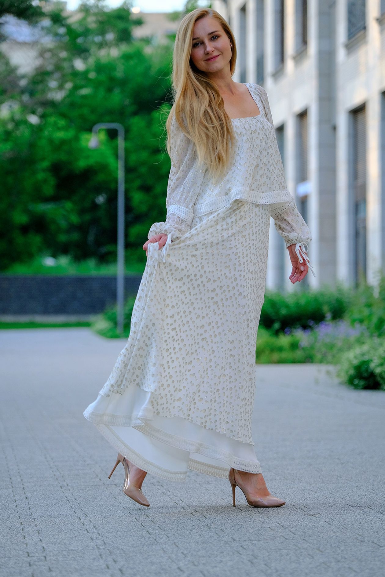 Woman wearing a white long-sleeve patterned maxi dress on a city street