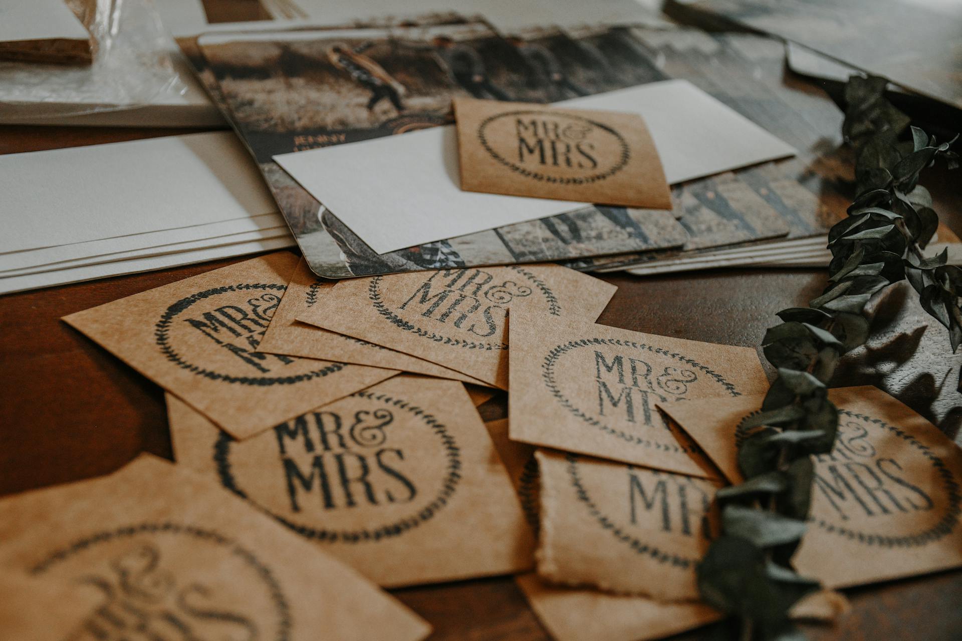 A collection of rustic wedding invitation cards with 'Mr & Mrs' text on a wooden table.