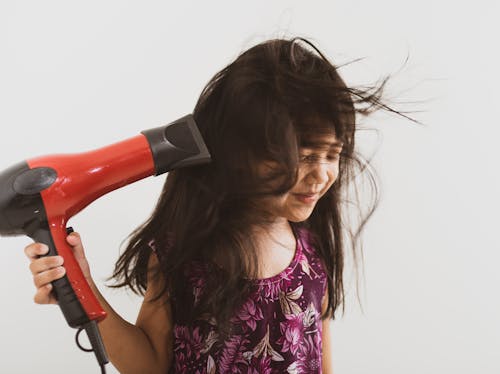 Free Close-Up Shot of a Girl in Floral Top Using a Hair Blower Stock Photo
