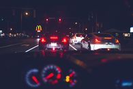 Stylish modern cars with glowing back lights driving on asphalt road in city at night
