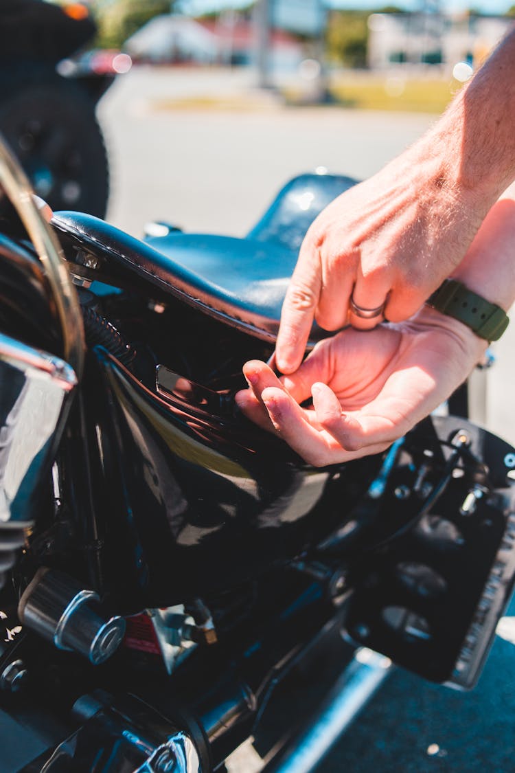 Crop Man Checking Motorbike Parked On Road In Sunlight