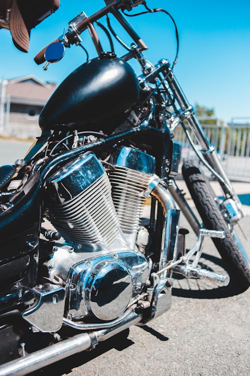 Exhaust system of modern motorbike parked on asphalt road in suburb against cloudless blue sky on sunny day