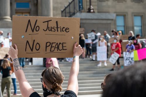 Free Anonymous social justice warriors in masks showing placards with No Justice No Peace title during manifestation in town Stock Photo
