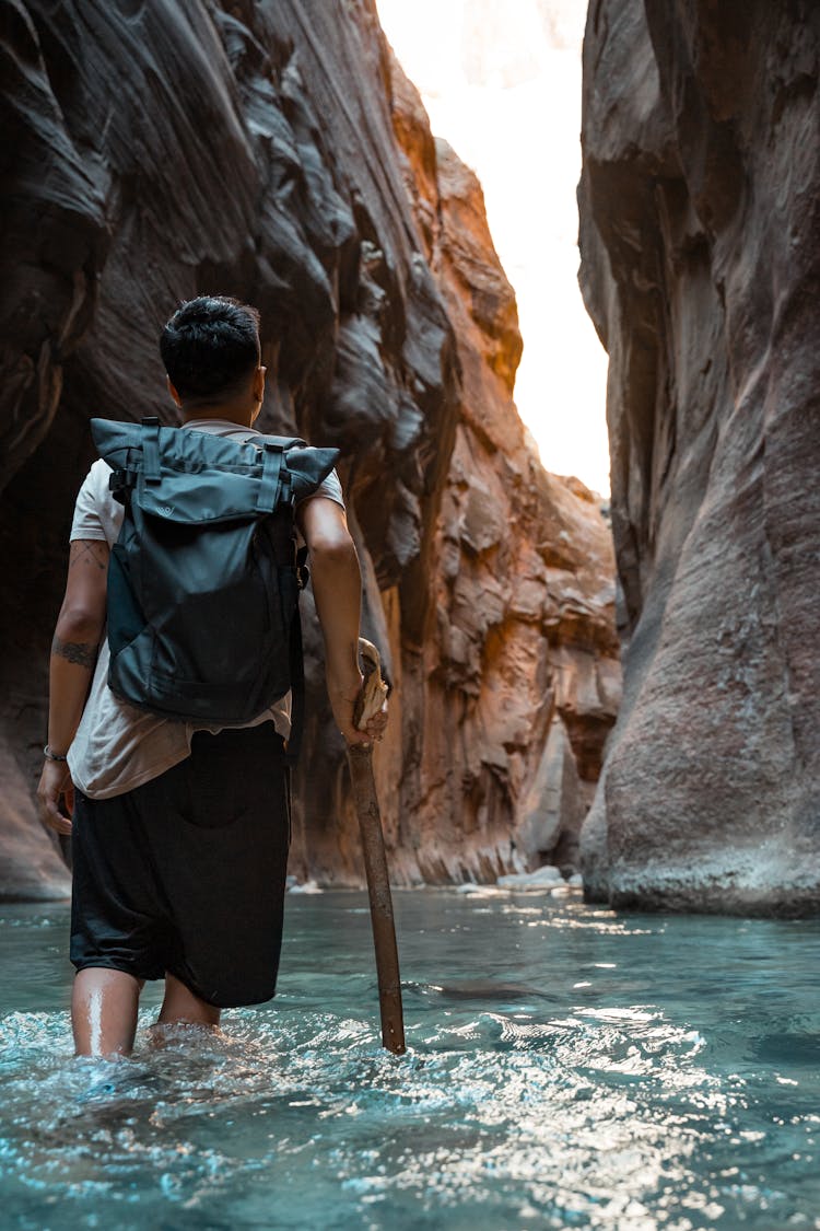 A Person Hiking Inside A Canyon In Utah