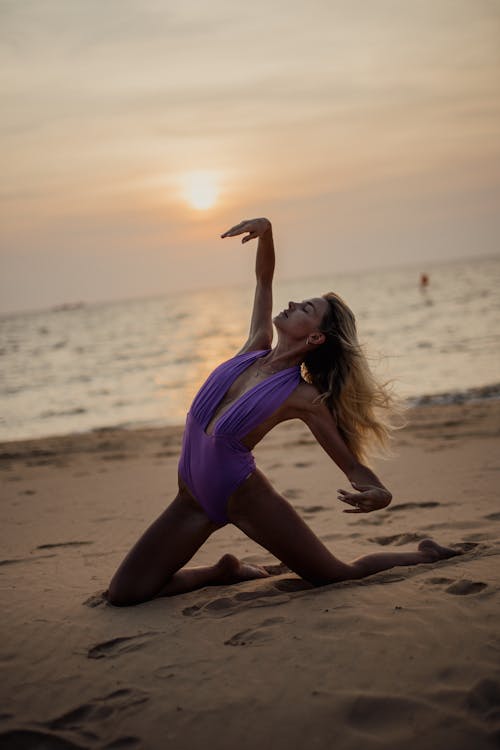 A Woman in Purple Swimsuit Posing at the Beach during Sunset