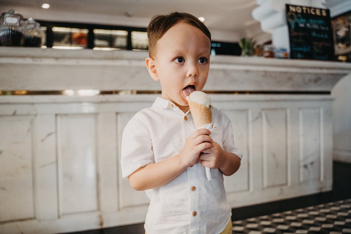 Close-Up Shot of a Cute Boy in White Button-Up Shirt Eating Ice Cream