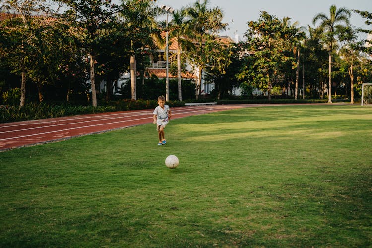 A Boy Playing Soccer On A Field