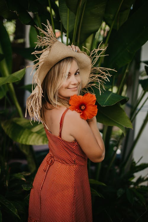 Donna In Vestito Senza Maniche Rosso Che Indossa Cappello Da Sole Marrone