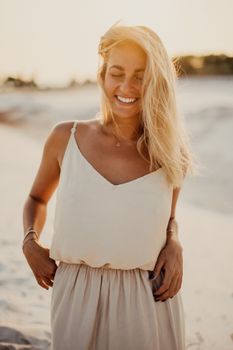 一个金发女人快乐地微笑着，在温暖的阳光海滩上拥抱夏天的共鸣