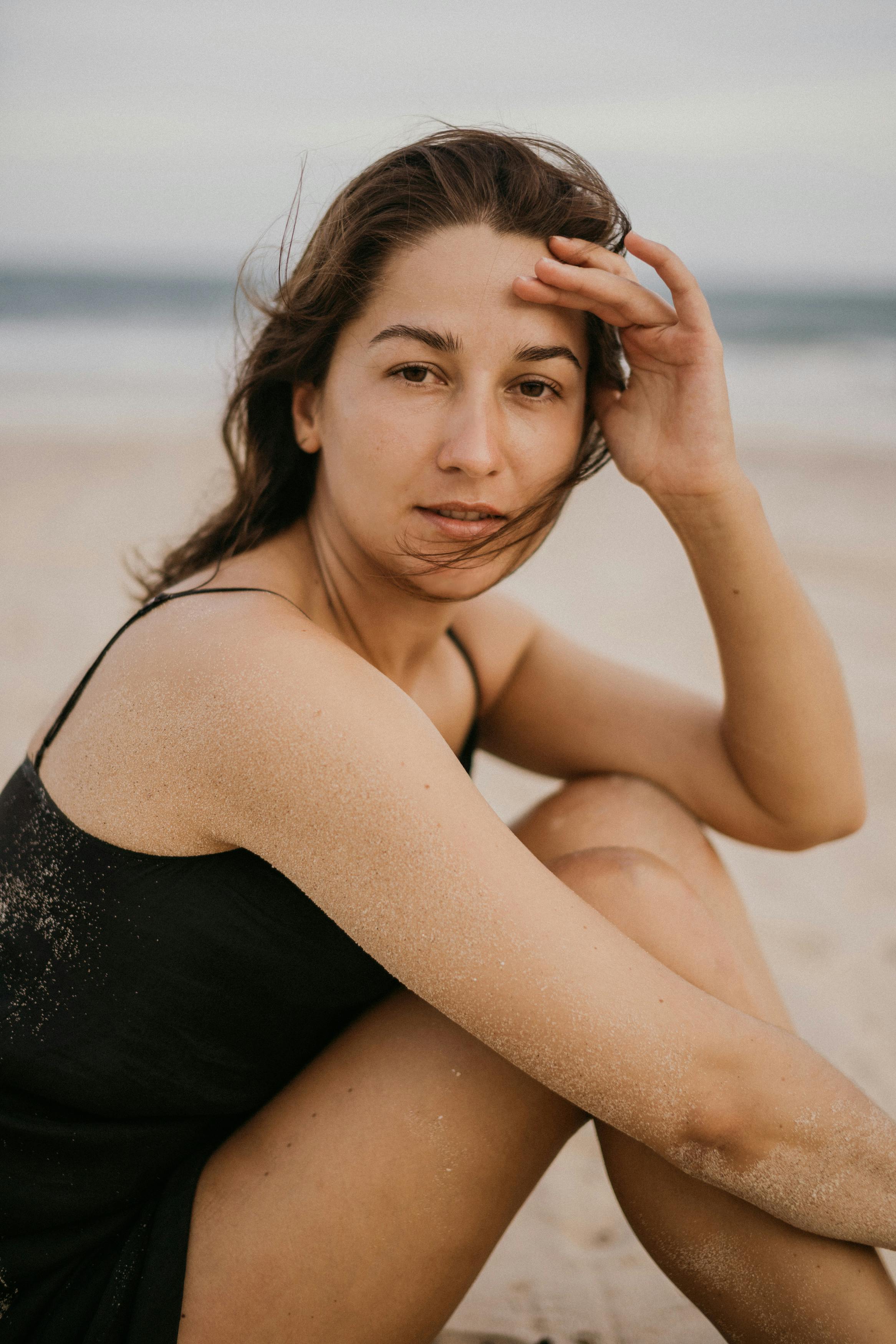 woman in black tank top sitting on the beach