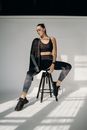 Woman in Black Tank Top and Black and White Striped Pants Sitting on Black Seat