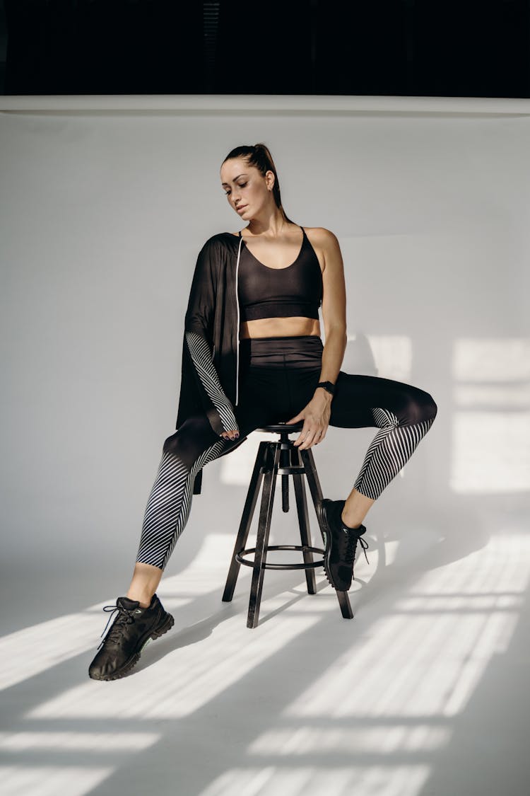 Woman In Black Sports Bra And Leggings Sitting On A Stool