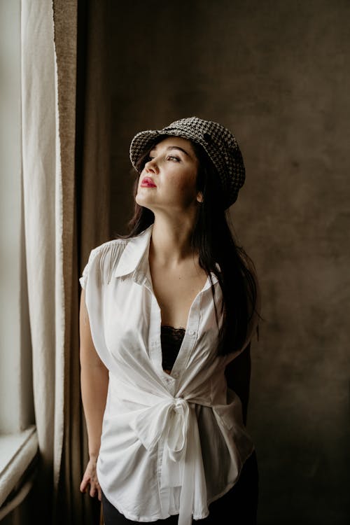 Free Woman in Knitted Cap Looking Outside the Window Stock Photo