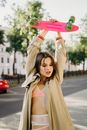 Woman in Brown Coat Holding Green and Black Skateboard