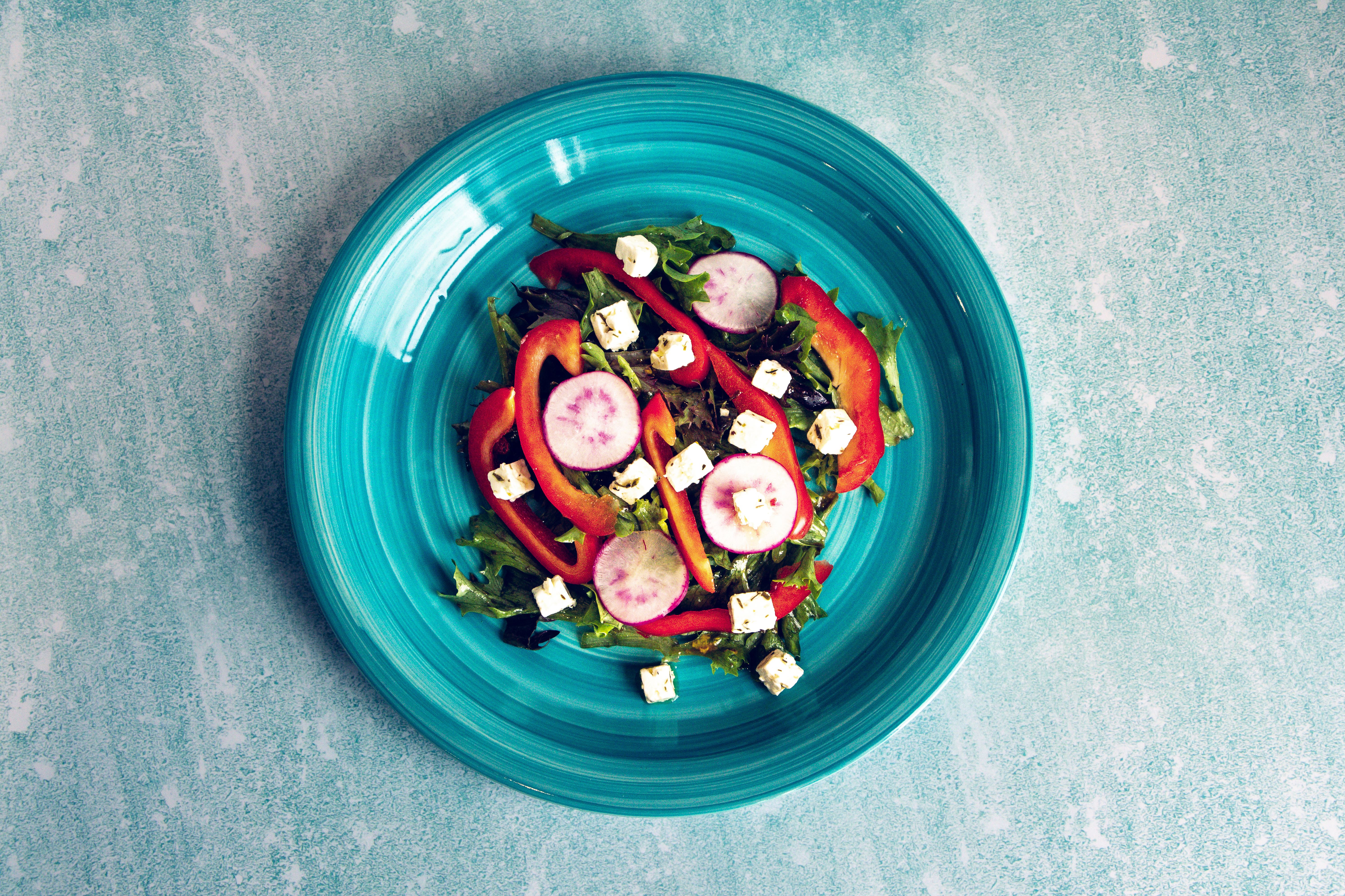 Colorful vegetable salad with feta and radishes on a blue plate. Perfect for healthy eating concepts.